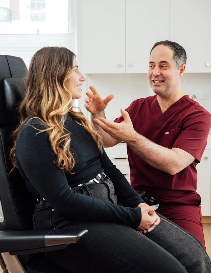 Dentist consulting with female patient in dental chair, explaining treatment options in modern clinic