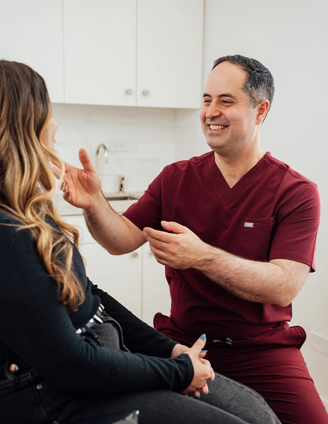 Healthcare professional in burgundy scrubs consulting with female patient in modern medical office