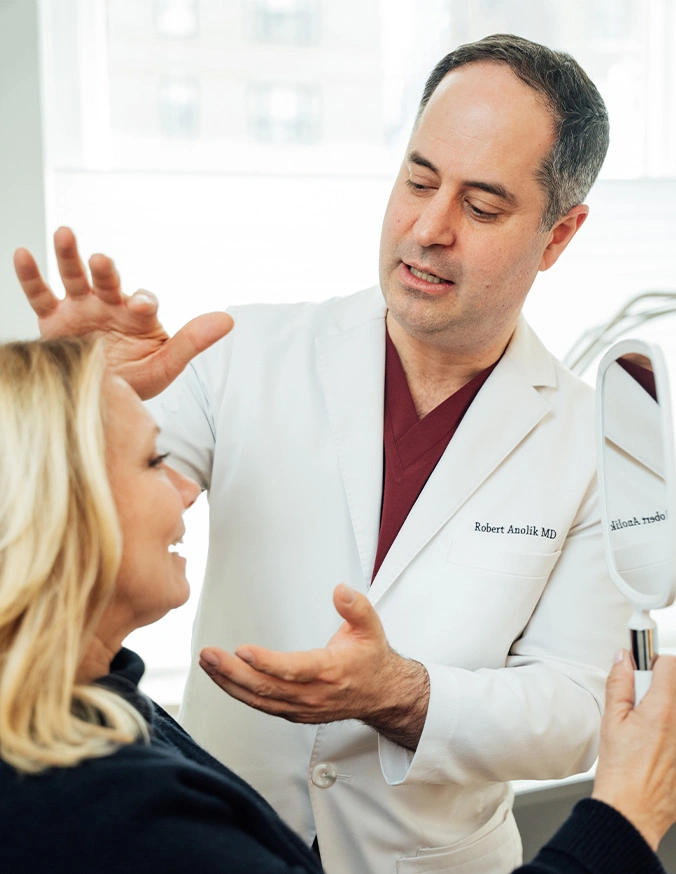 Plastic surgeon consulting with female patient about facial procedure in medical office