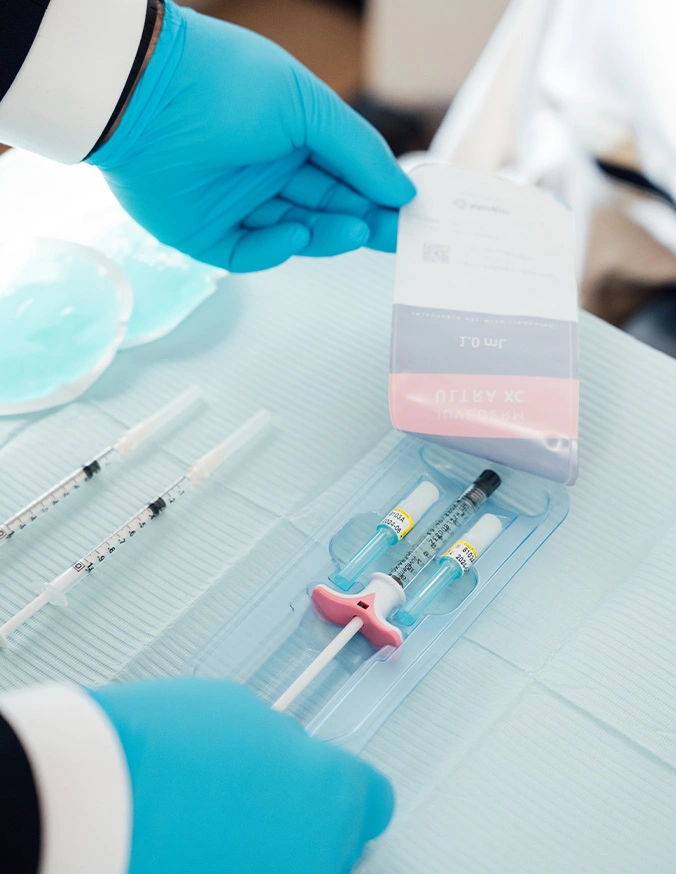 Laboratory technician in blue gloves preparing medical samples with syringes and vials for testing