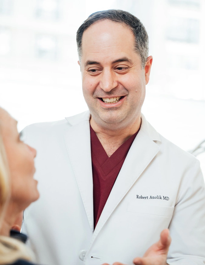 Doctor in white coat smiling while consulting with patient in medical office setting