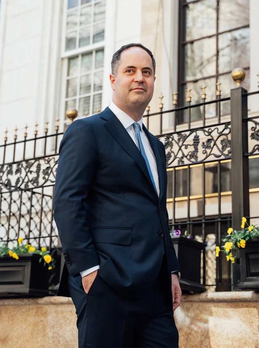 Professional businessman in navy suit standing outside historic building with iron railings