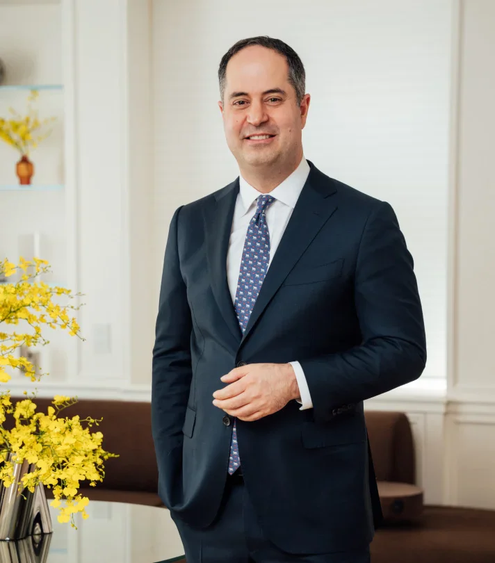 Professional male surgeon in navy suit standing confidently in medical office with yellow flowers