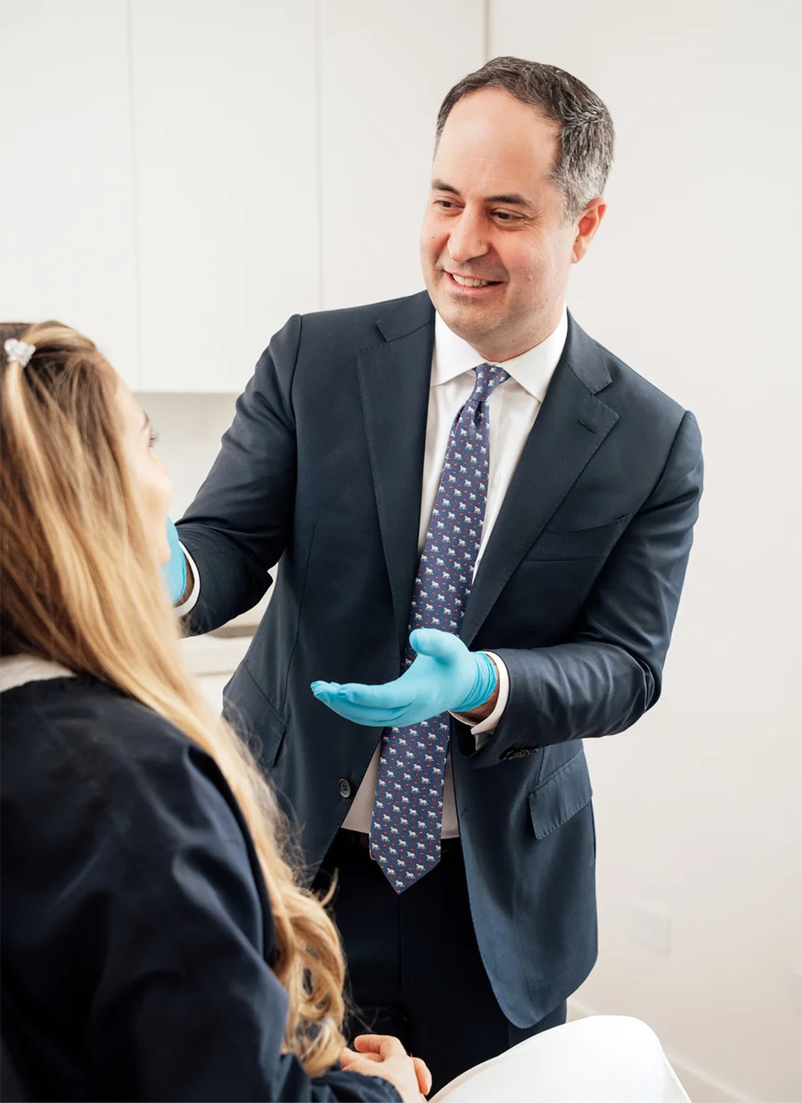 Medical professional in suit consulting with patient while holding blue medical gloves in clinical setting