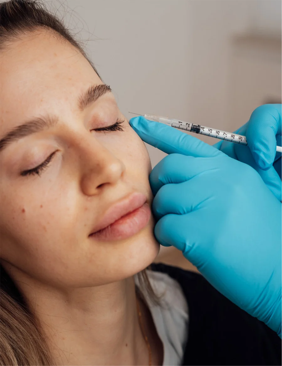 Woman receiving cosmetic facial injection treatment from medical professional wearing blue gloves
